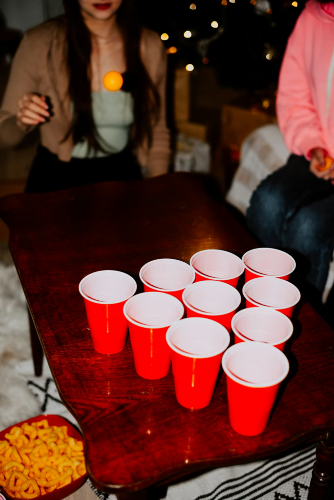 image d'une partie de beer pong entre amis qui fait rebondir la balle de ping pong dans les verres de bières